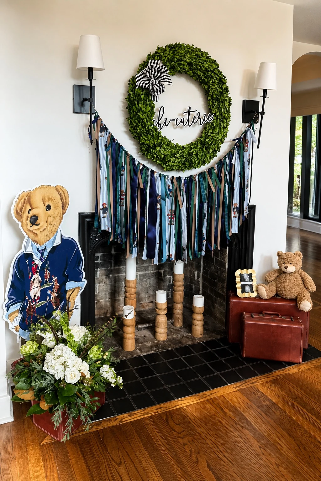 Fireplace vignette with wreath, ribbon garland, florals, teddy-bear character, and vintage suitcases