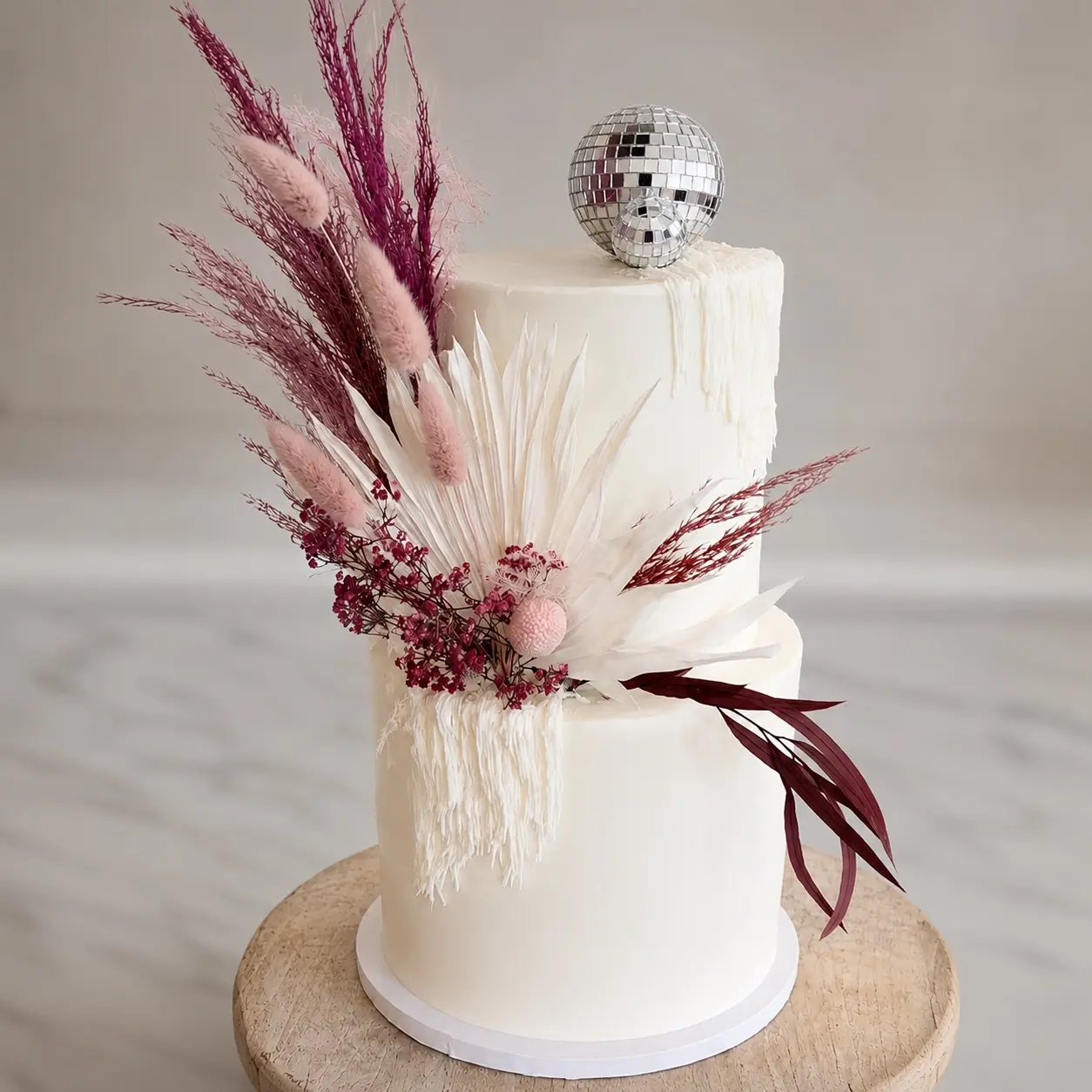 Two-tier celebration cake finished with dried florals and mirrored disco balls