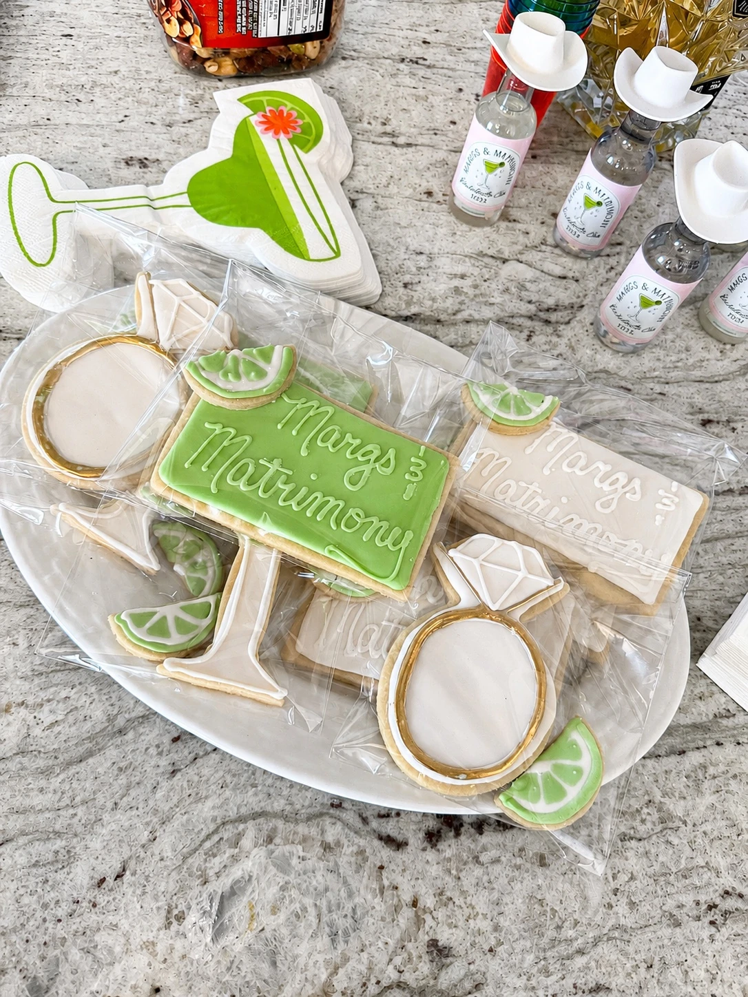 Close-up of custom Margs and Matrimony cookies and themed mini bottles