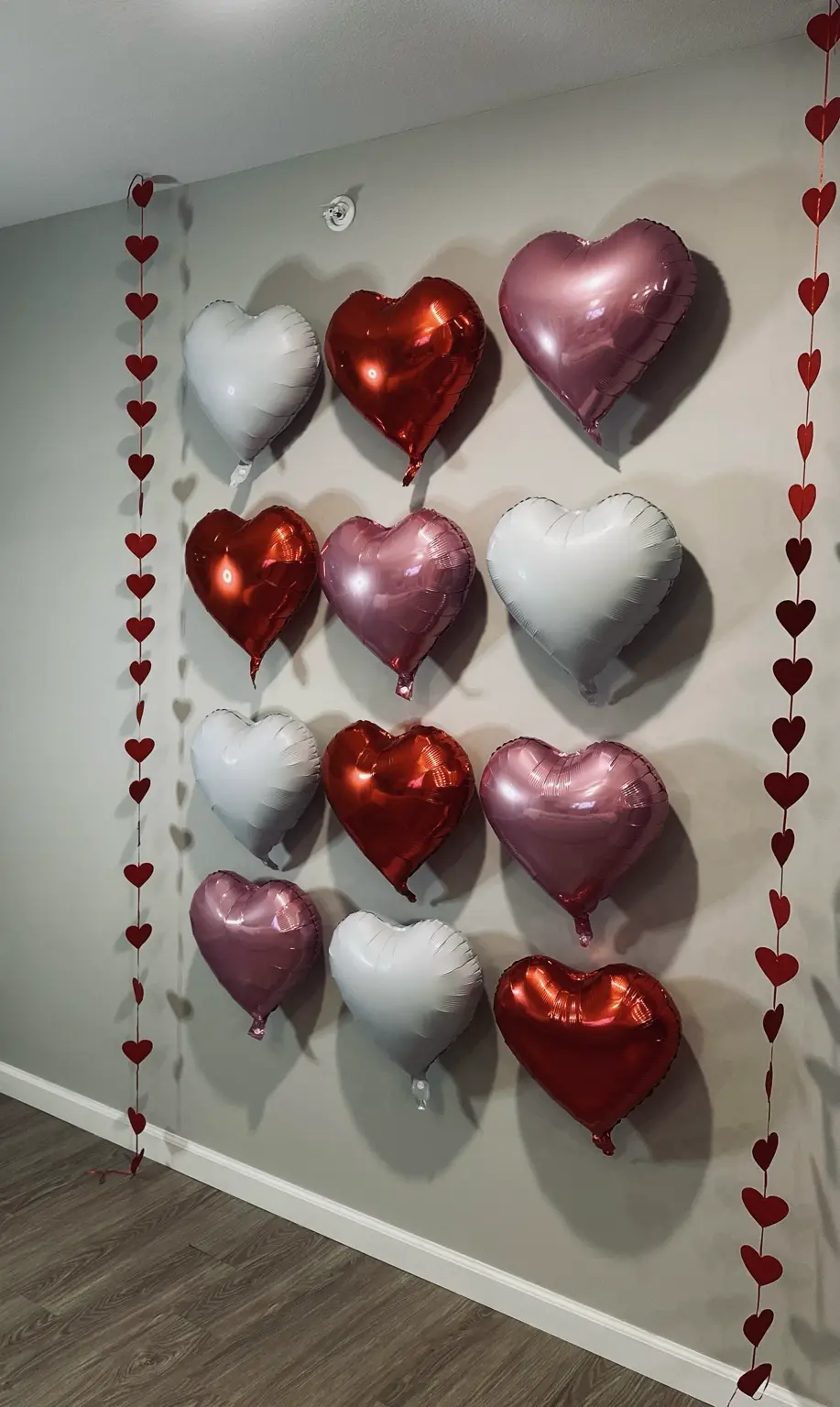 Wall of red, pink, and white heart balloons framed by red heart garlands