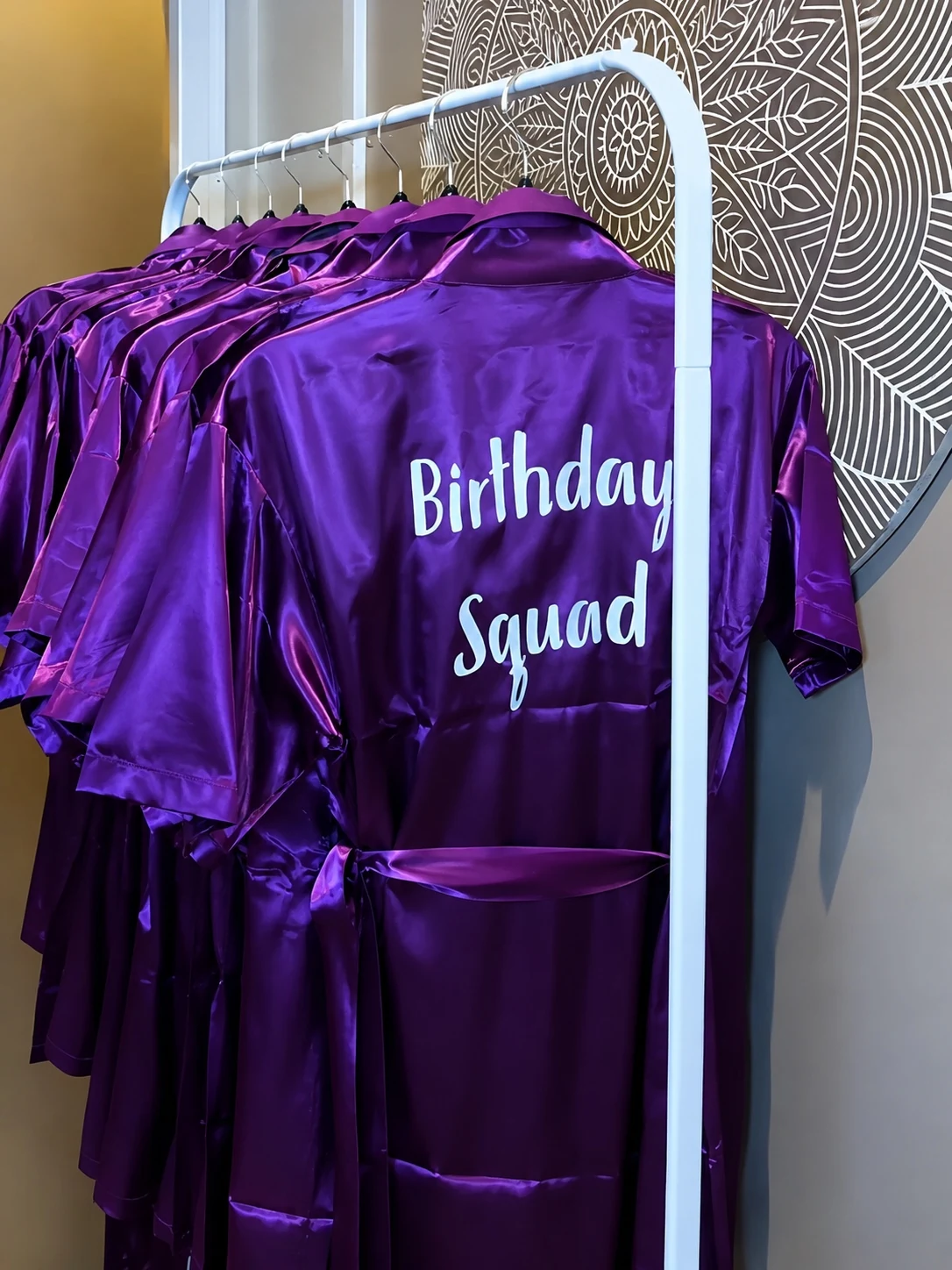 Purple satin robes on a rack for the birthday squad