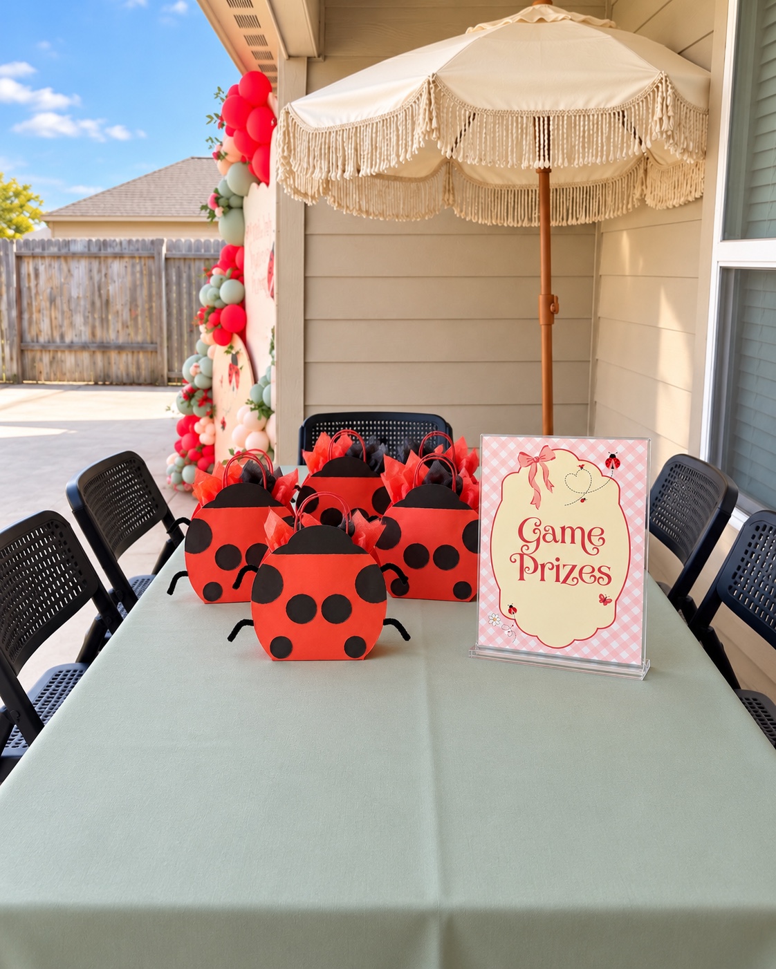 Outdoor game prize table with ladybug treat bags and acrylic game prize sign