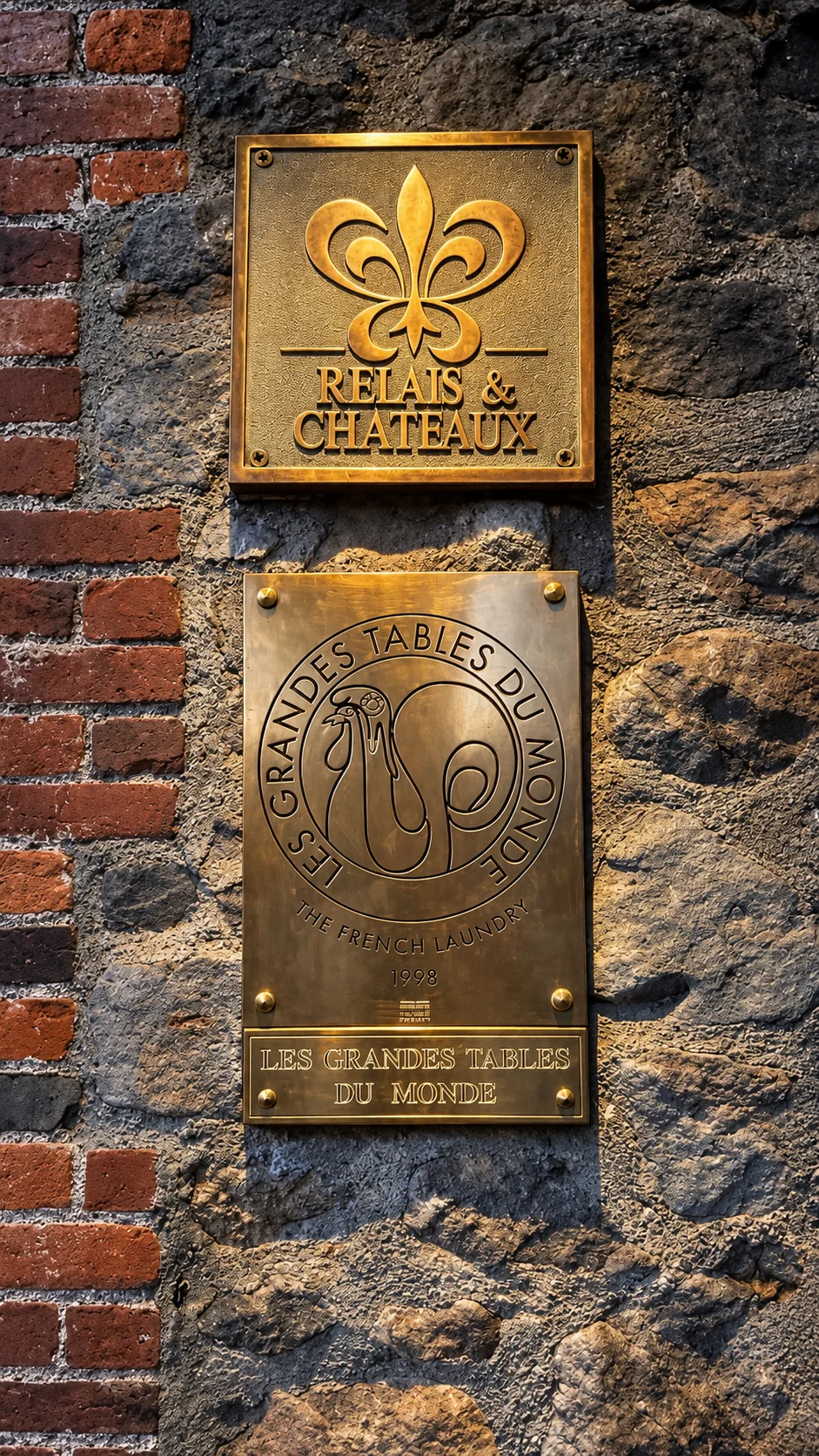 Relais & Châteaux and Les Grandes Tables du Monde plaques on the historic stone wall