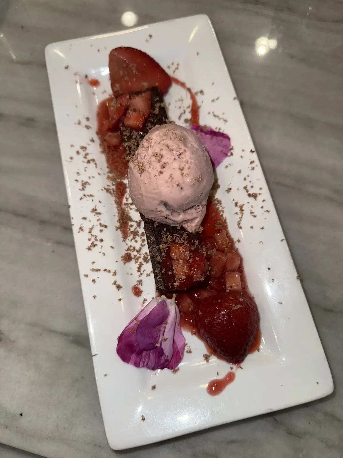 A plated dessert with strawberries and chocolate
